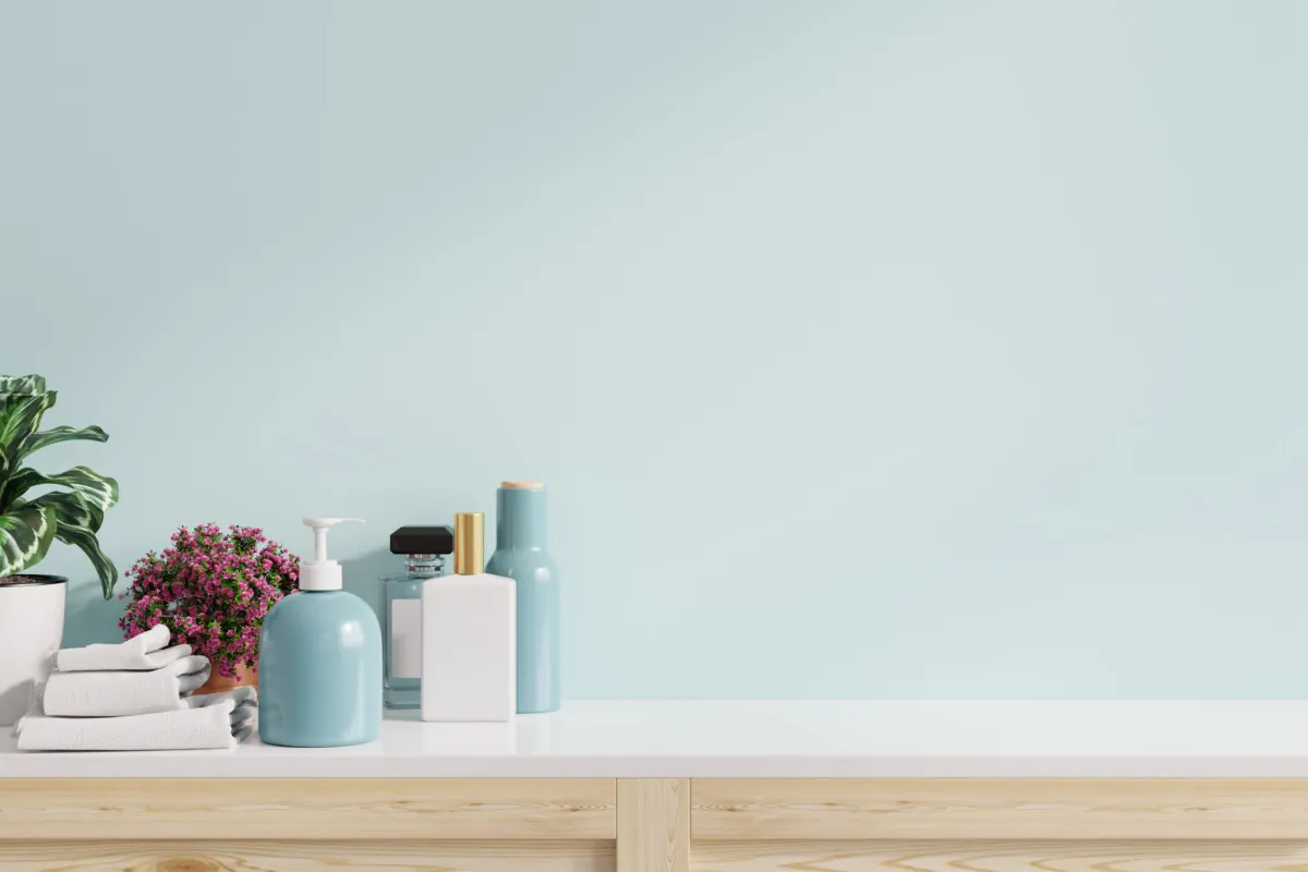 Accessories on white shelf in bathroom interior on blue wall.